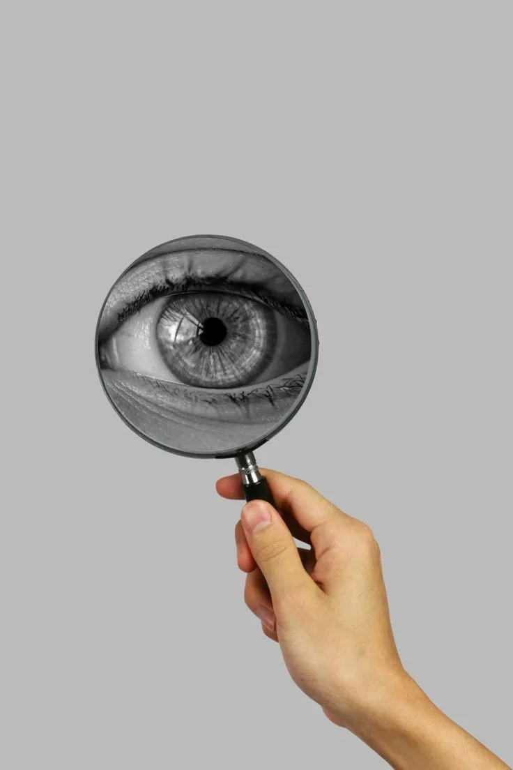Mano sosteniendo una lupa frente a un ojo